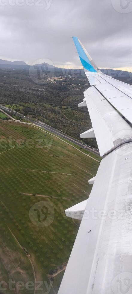 View from the window onto the wing of an airplane during a flight above the ground photo