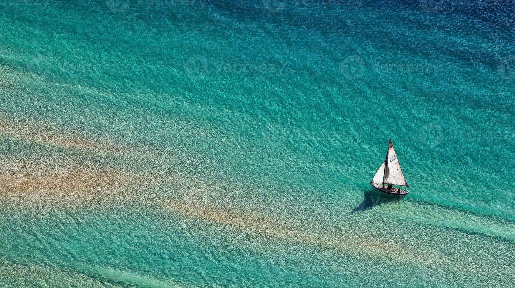 Aerial View of a Lone Sailboat on a Turquoise Ocean photo