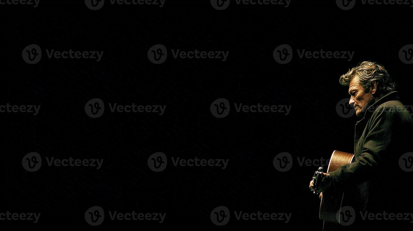 Dramatic Low Light Portrait of Musician Playing Acoustic Guitar on Dark Stage photo