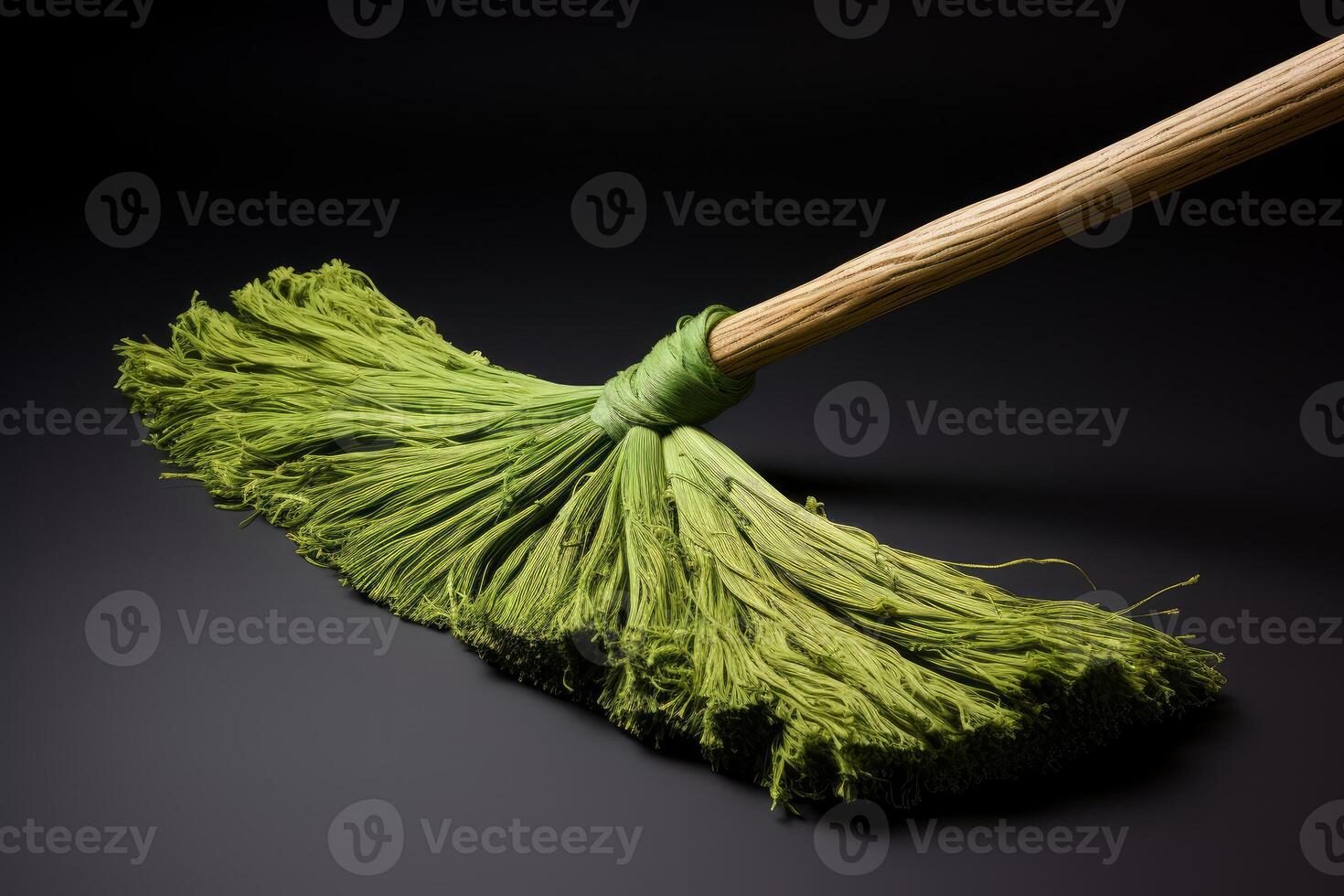Green broom sweeping on black background with wooden handle photo