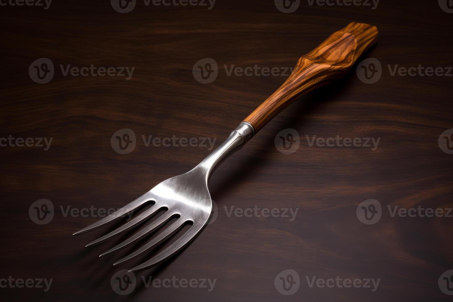 Elegant serving fork with wooden handle resting on dark wood surface photo