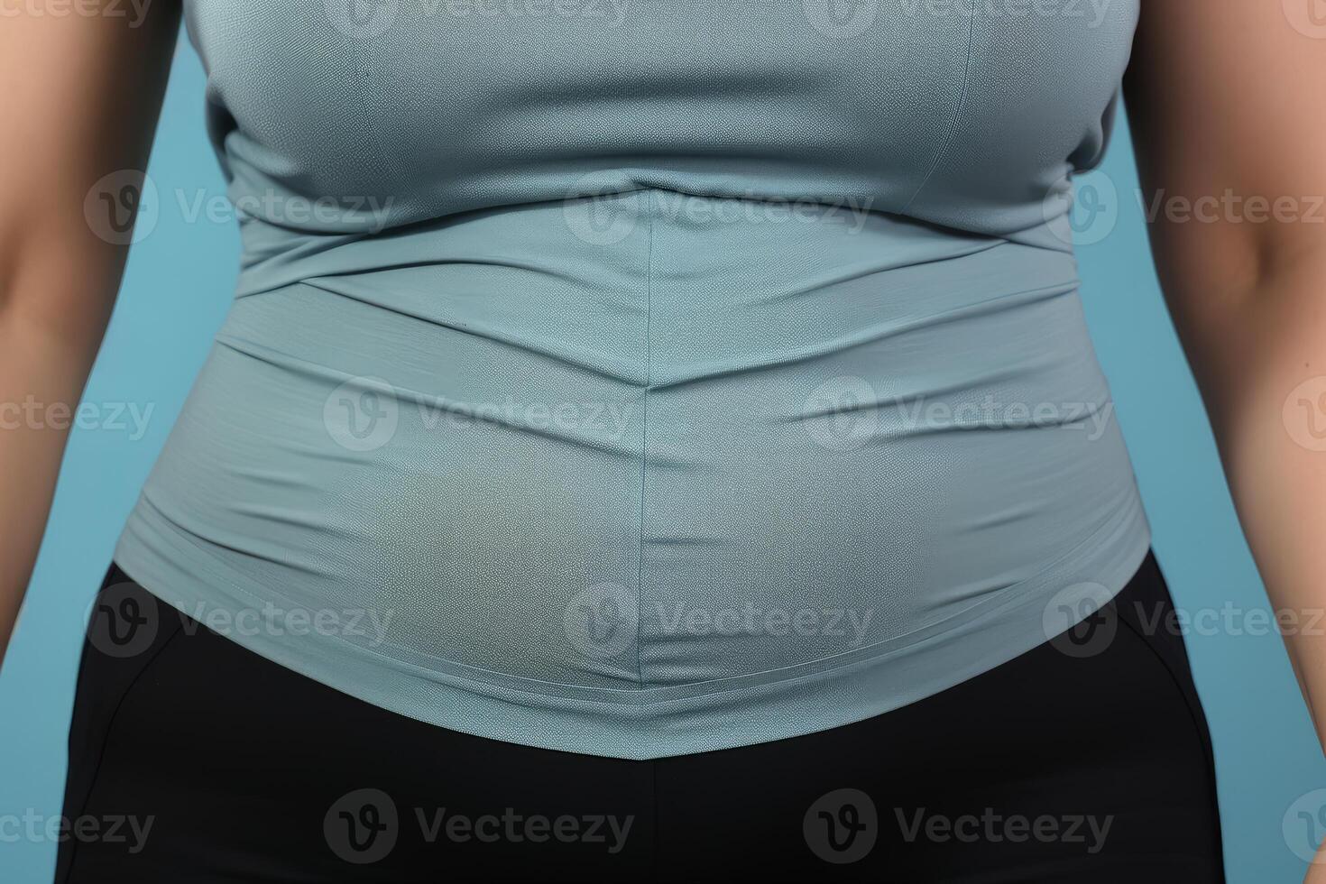 Overweight woman showing belly fat on blue background photo