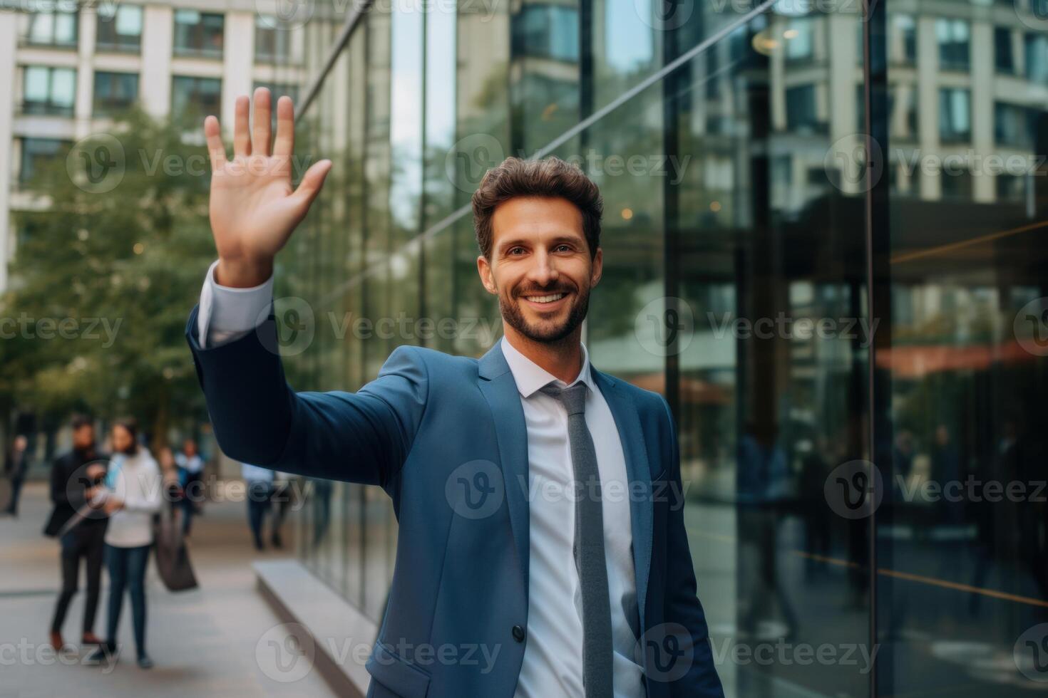 Smiling businessman waving hand in front of office building photo