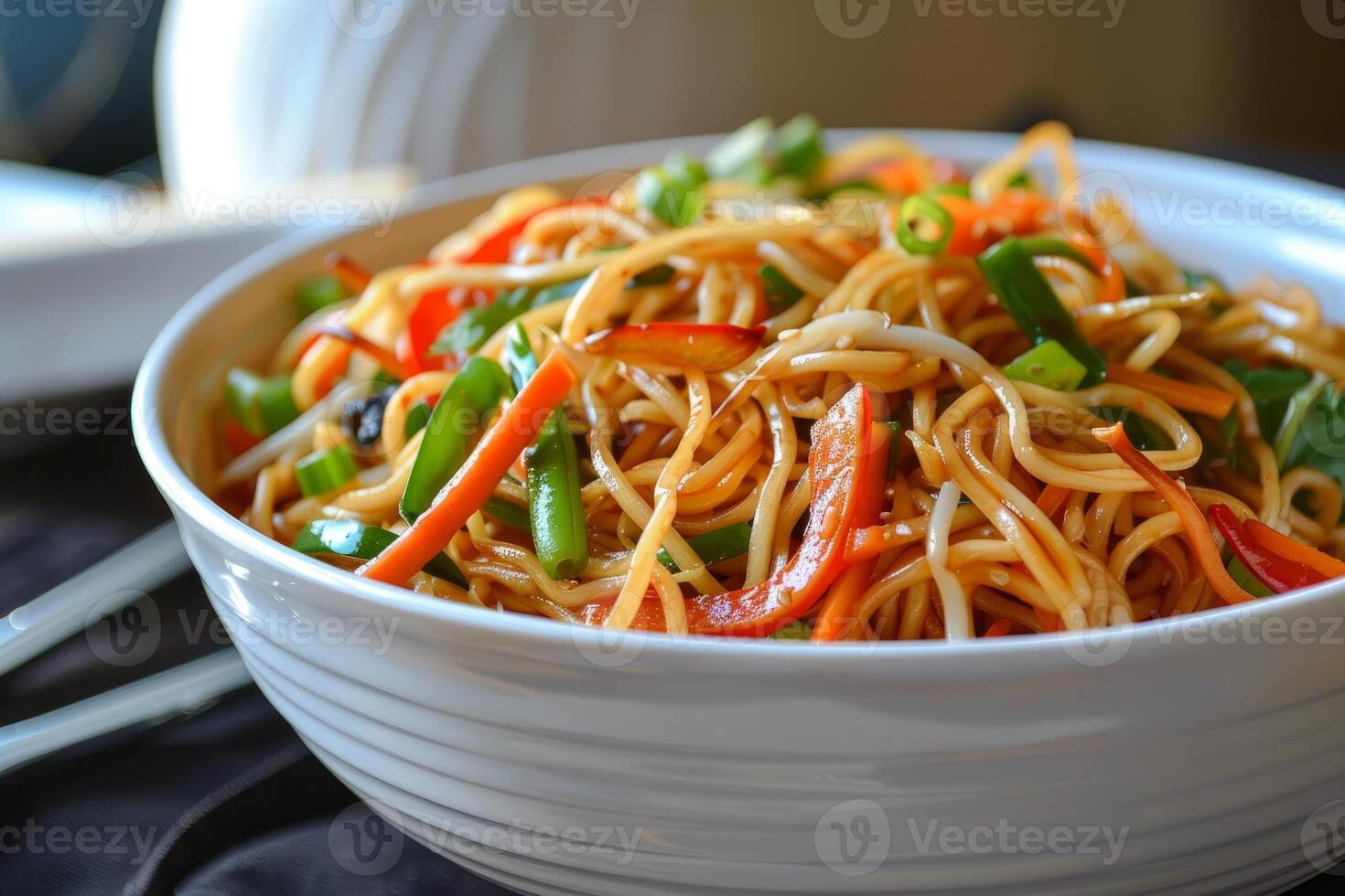 Chow mein noodles with colorful vegetables in white bowl being served photo