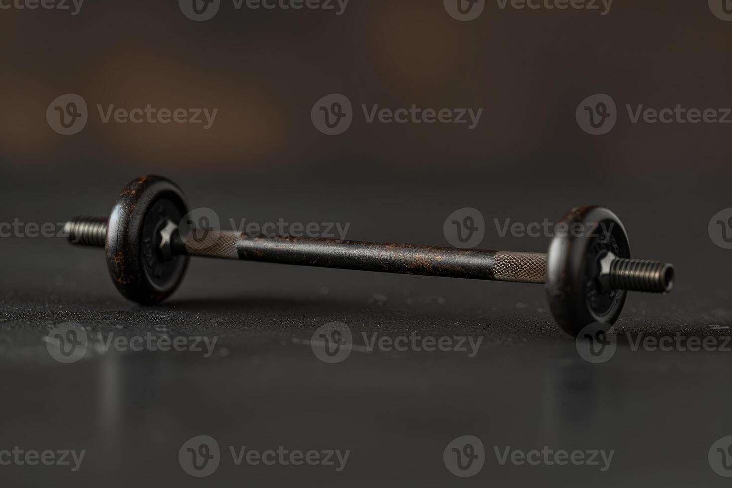 Small black dumbbell resting on dark surface promoting fitness and strength training photo