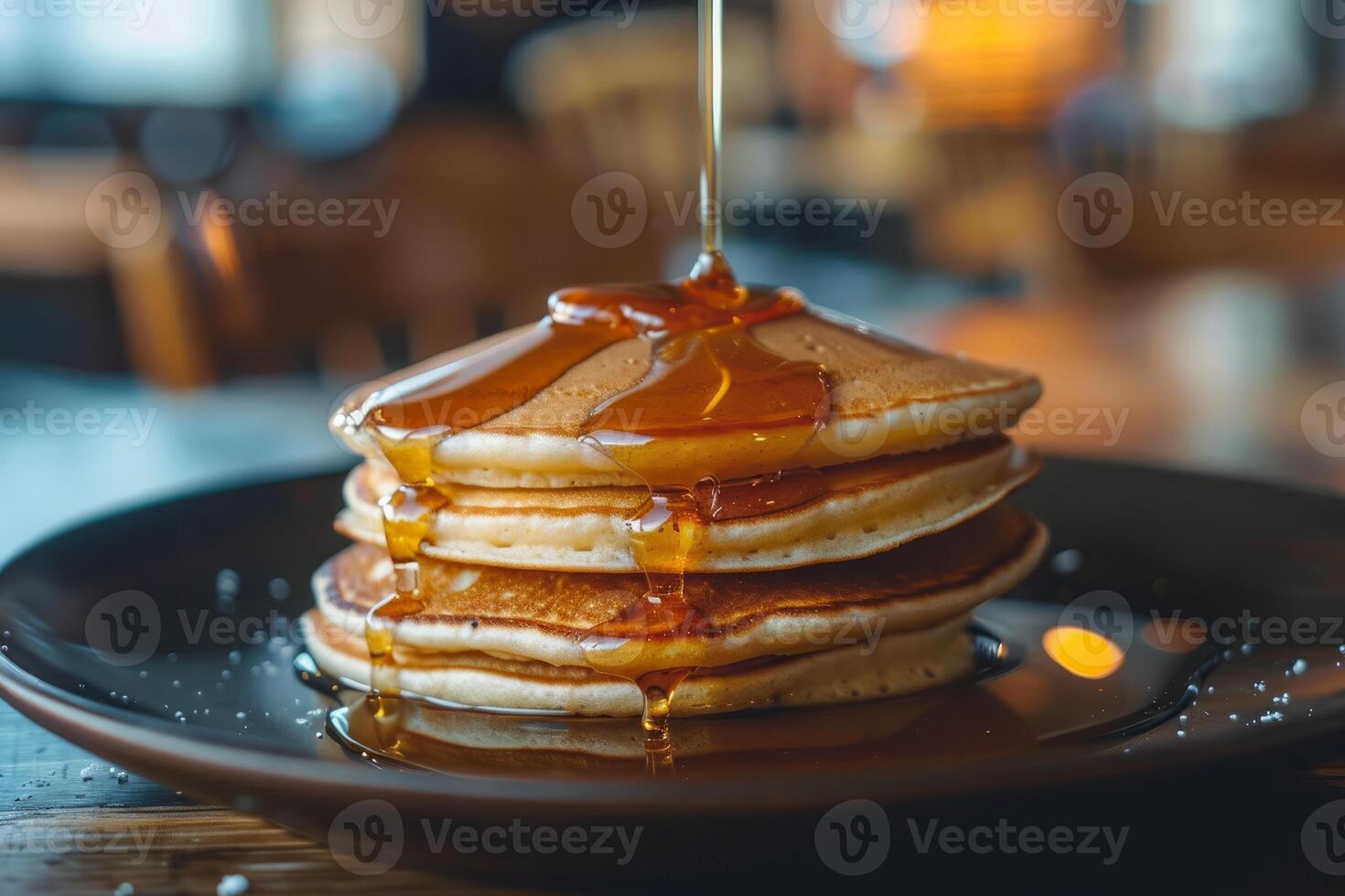 Stack of pancakes being drizzled with maple syrup in a restaurant photo