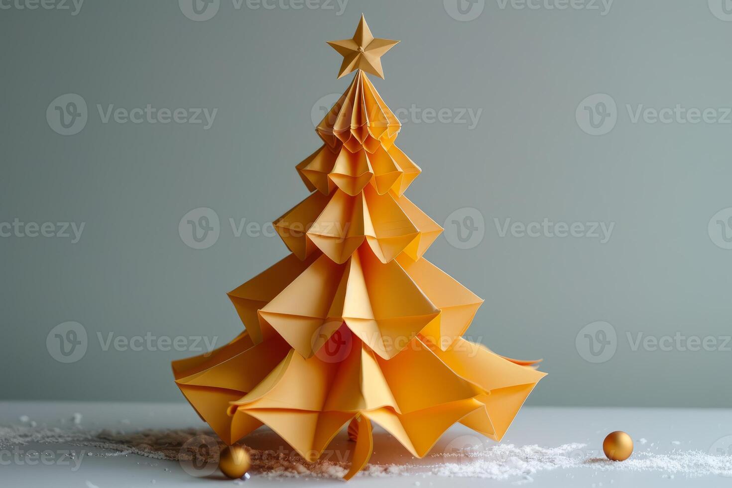Golden origami christmas tree standing on snowy surface with golden balls photo
