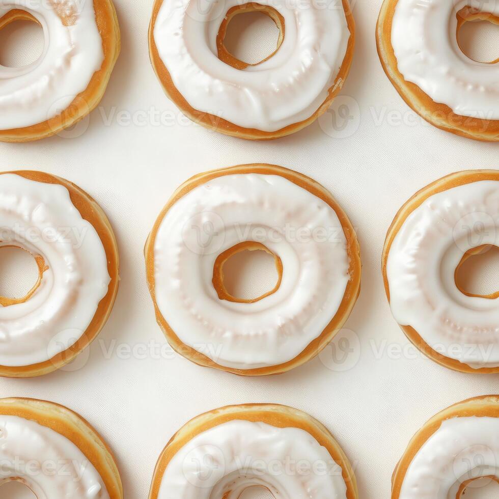 Delicious glazed donuts forming repeating pattern on white background photo