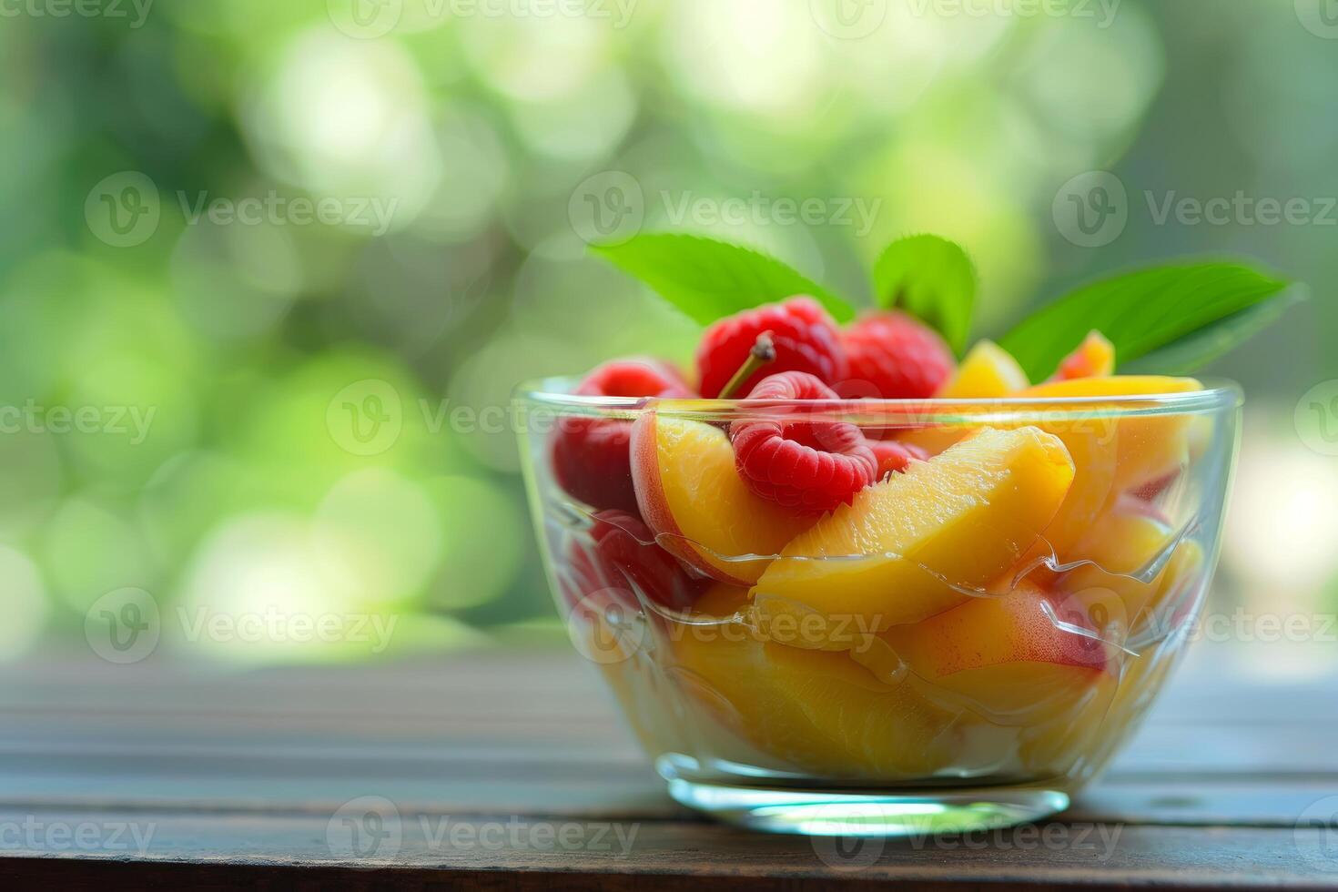 Glass bowl overflowing with fresh peaches and raspberries on wooden table photo