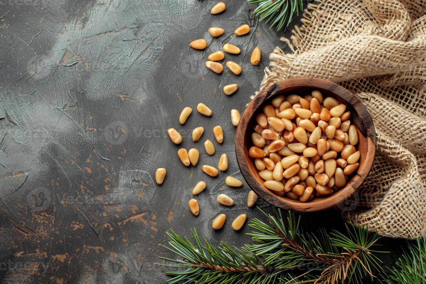 Pine nuts in wooden bowl decorated with pine branches on dark background photo