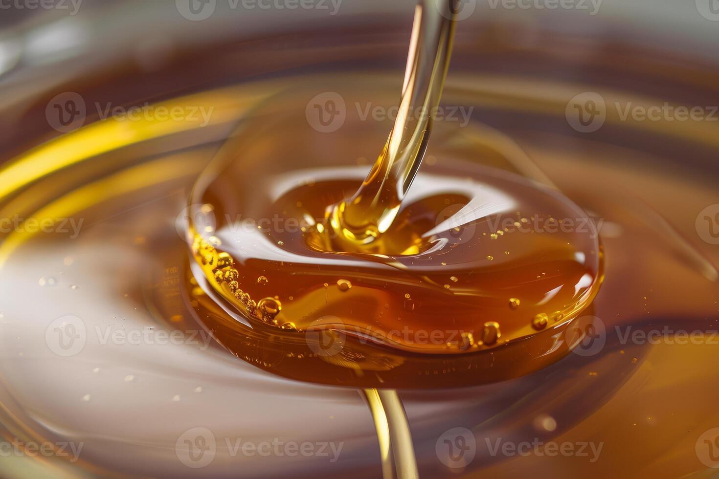 Thick, golden honey pouring and creating bubbles in a bowl photo