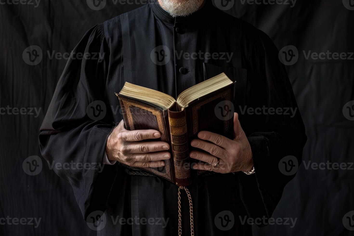 Priest wearing cassock holding open book in church photo