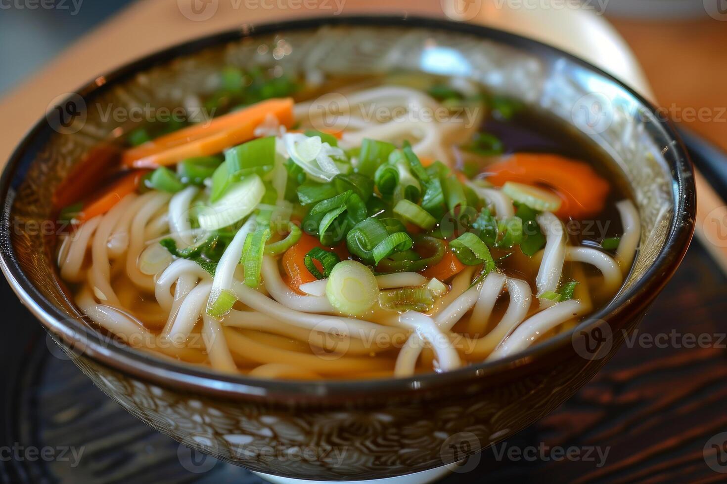 Steaming bowl of udon noodles with chopped scallions and carrots photo