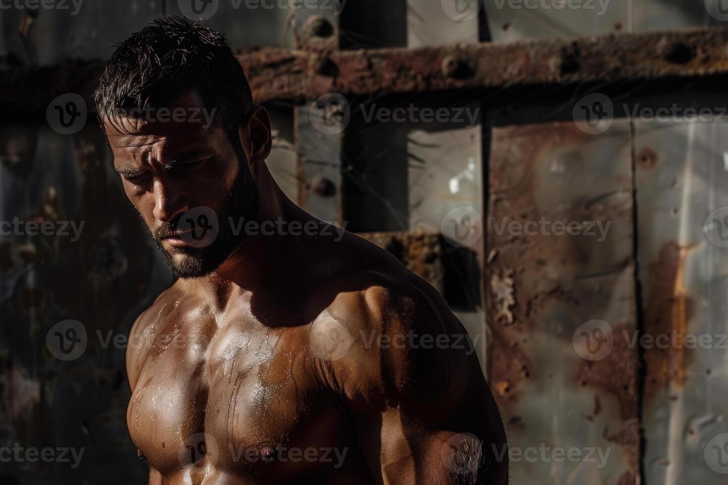 Muscular man sweating and posing in industrial setting photo