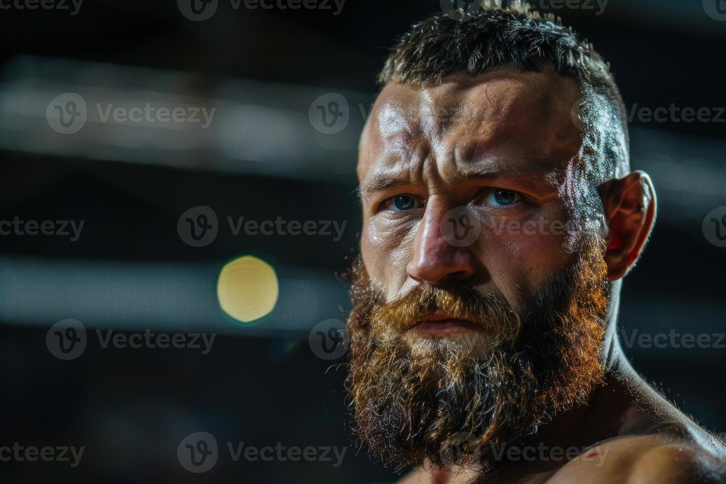 Portrait of serious male boxer with beard showing fighting spirit in gym photo