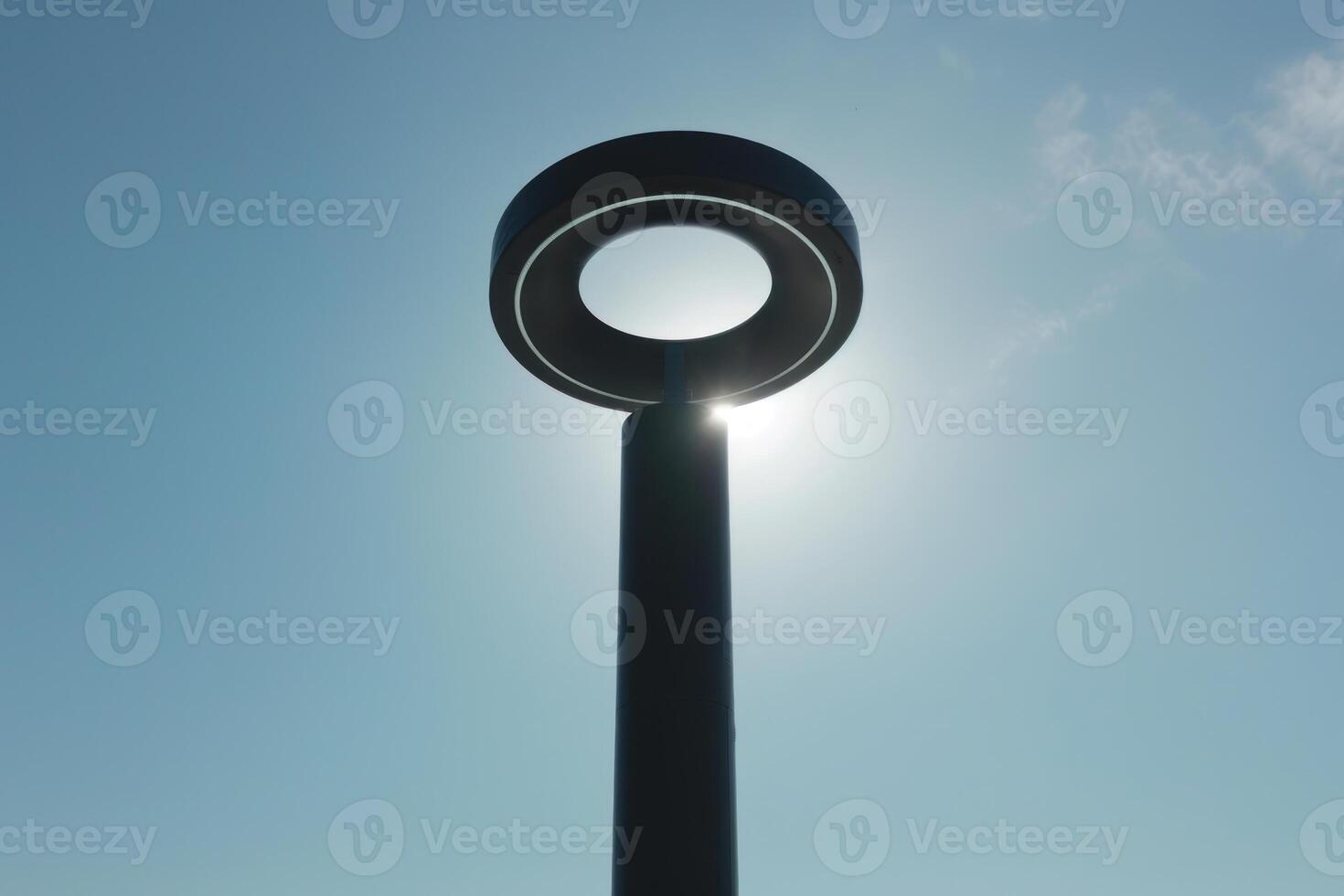 Modern circular street lamp illuminating a clear blue sky photo