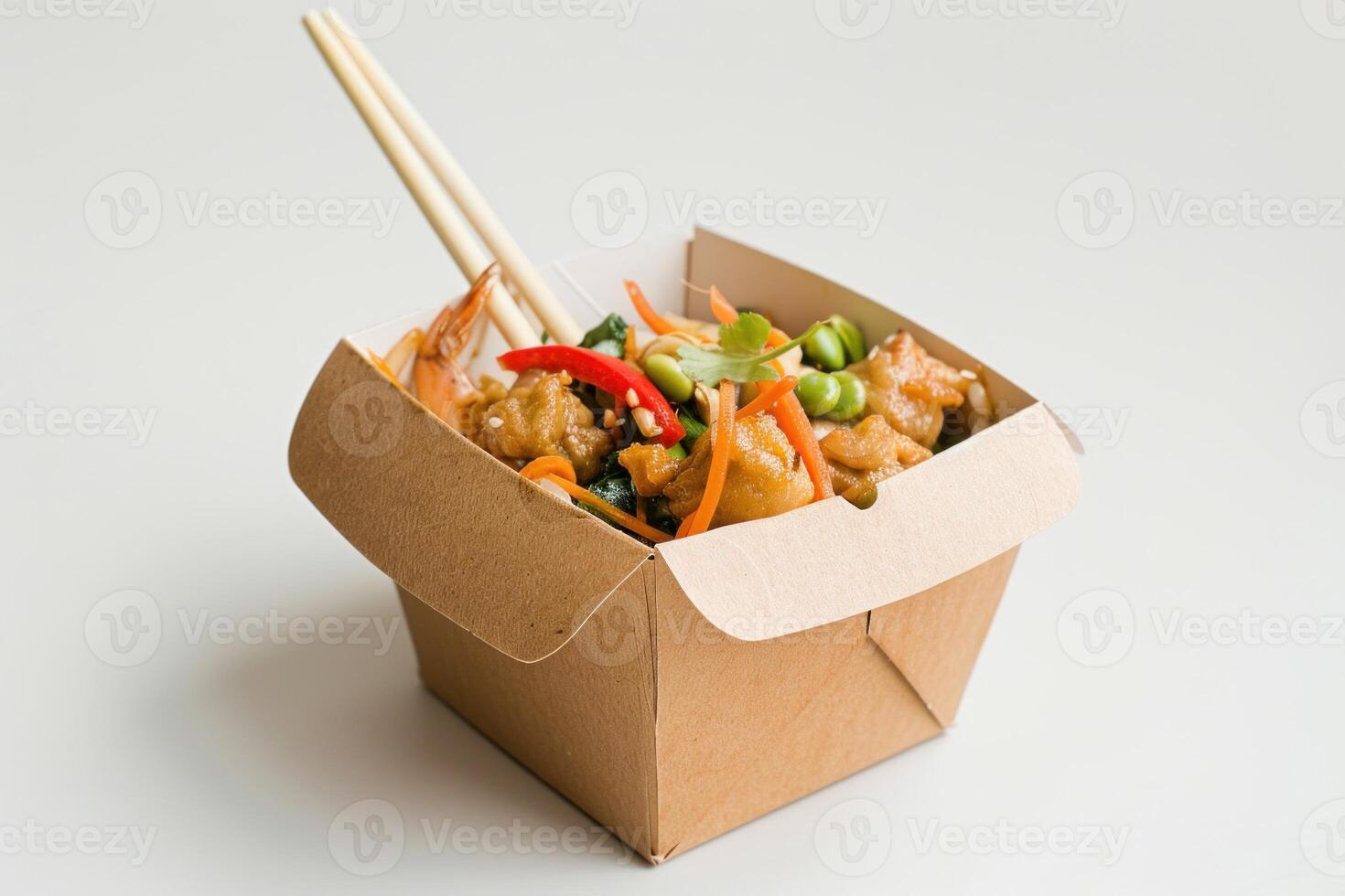 Wok in a cardboard box with chopsticks, vegetables, shrimp, and chicken photo