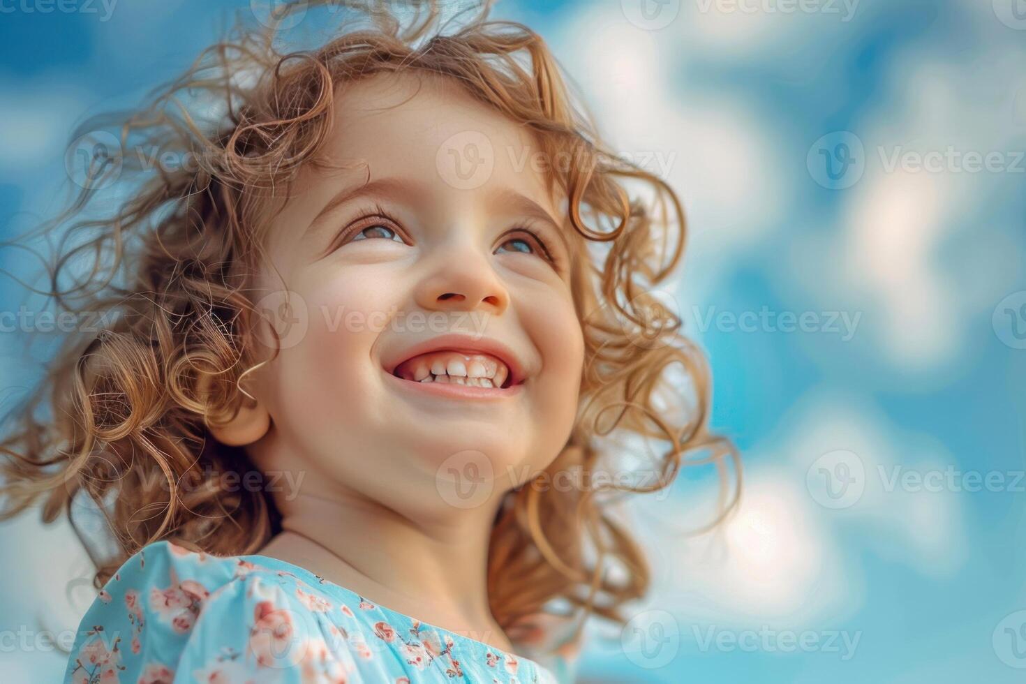 Portrait of smiling toddler girl looking up at sky with hope and happiness photo