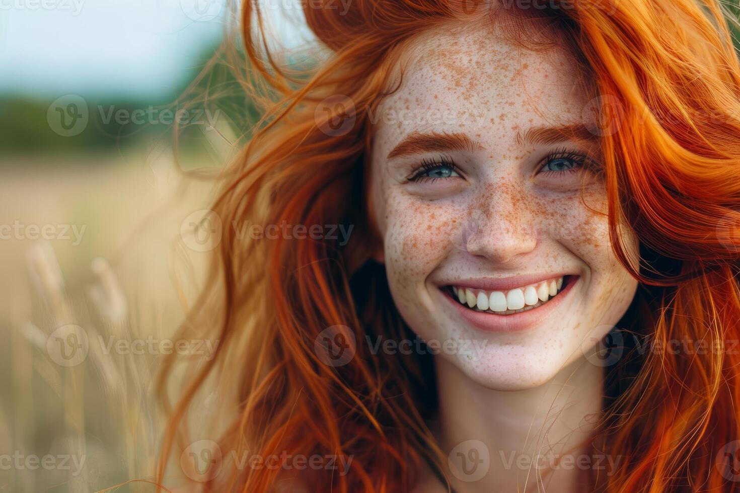 Happy redhead woman smiling with freckles in a wheat field photo