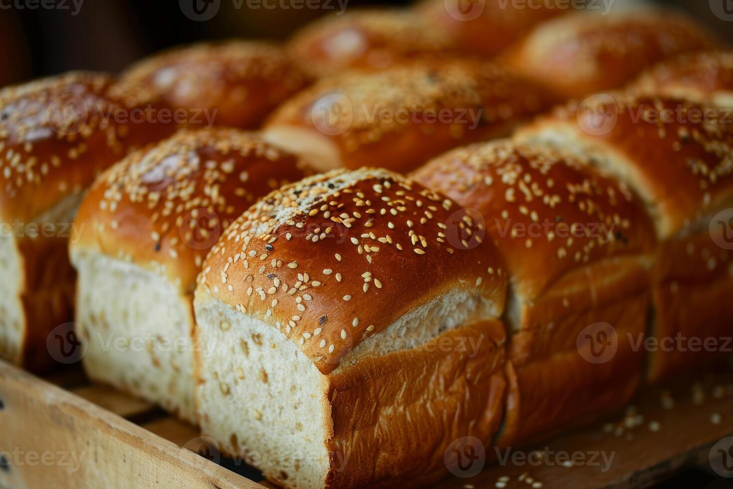 Freshly baked square loaves of bread topped with sesame seeds resting on wooden crate photo
