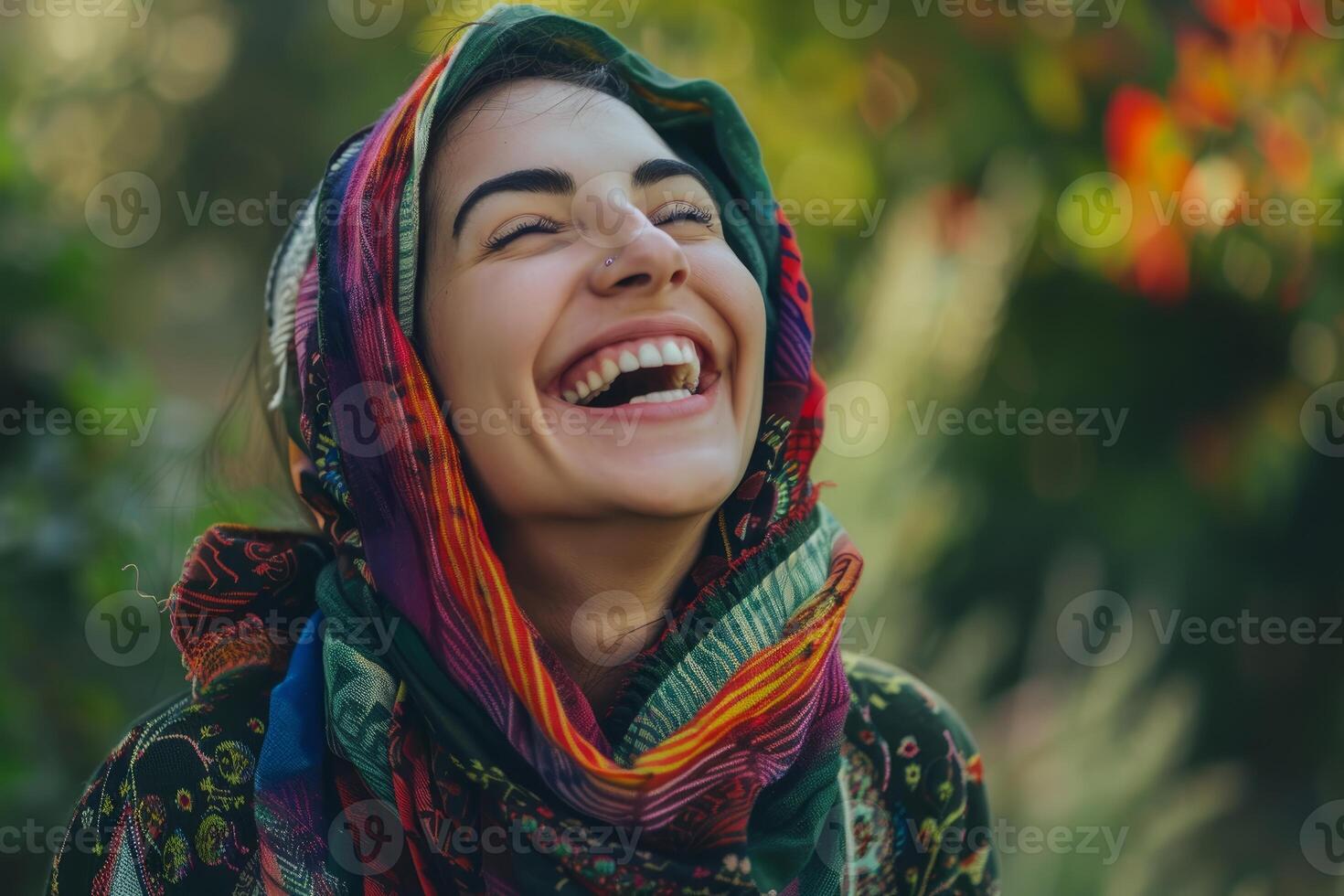 Young woman wearing colorful scarf is laughing in nature photo