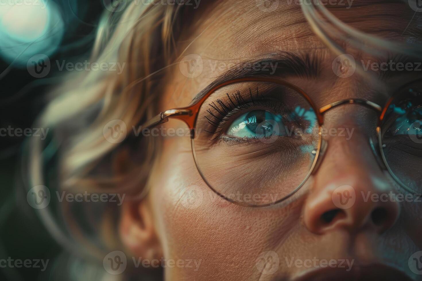 Woman wearing glasses is looking up in wonder at night lights reflecting in her eyes photo