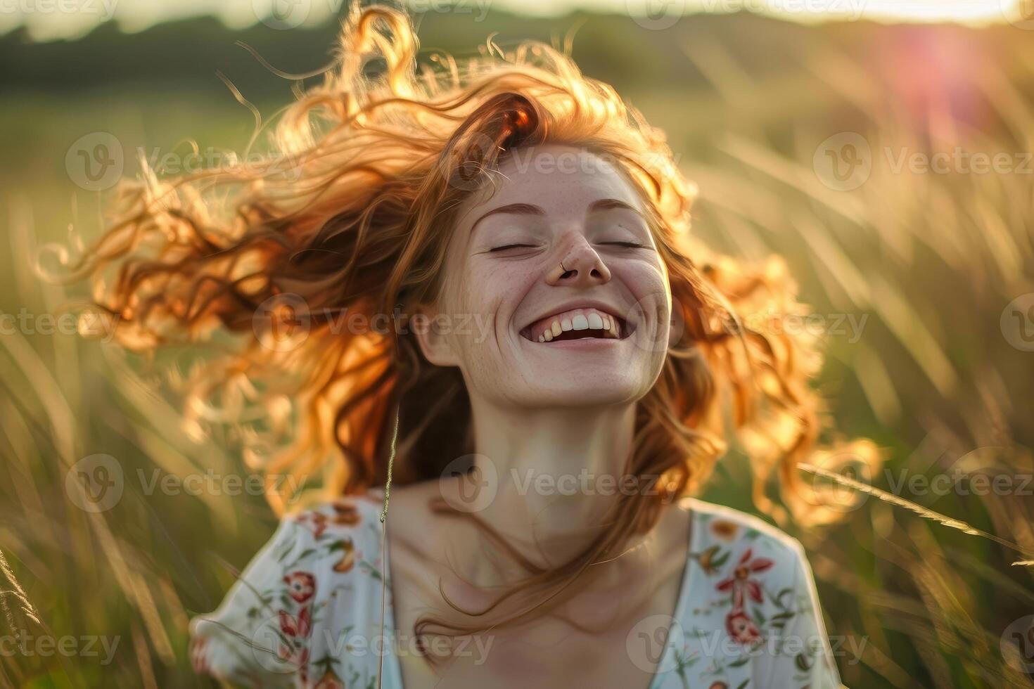 Happy redhead woman enjoying the sunset in a field with flying hair photo