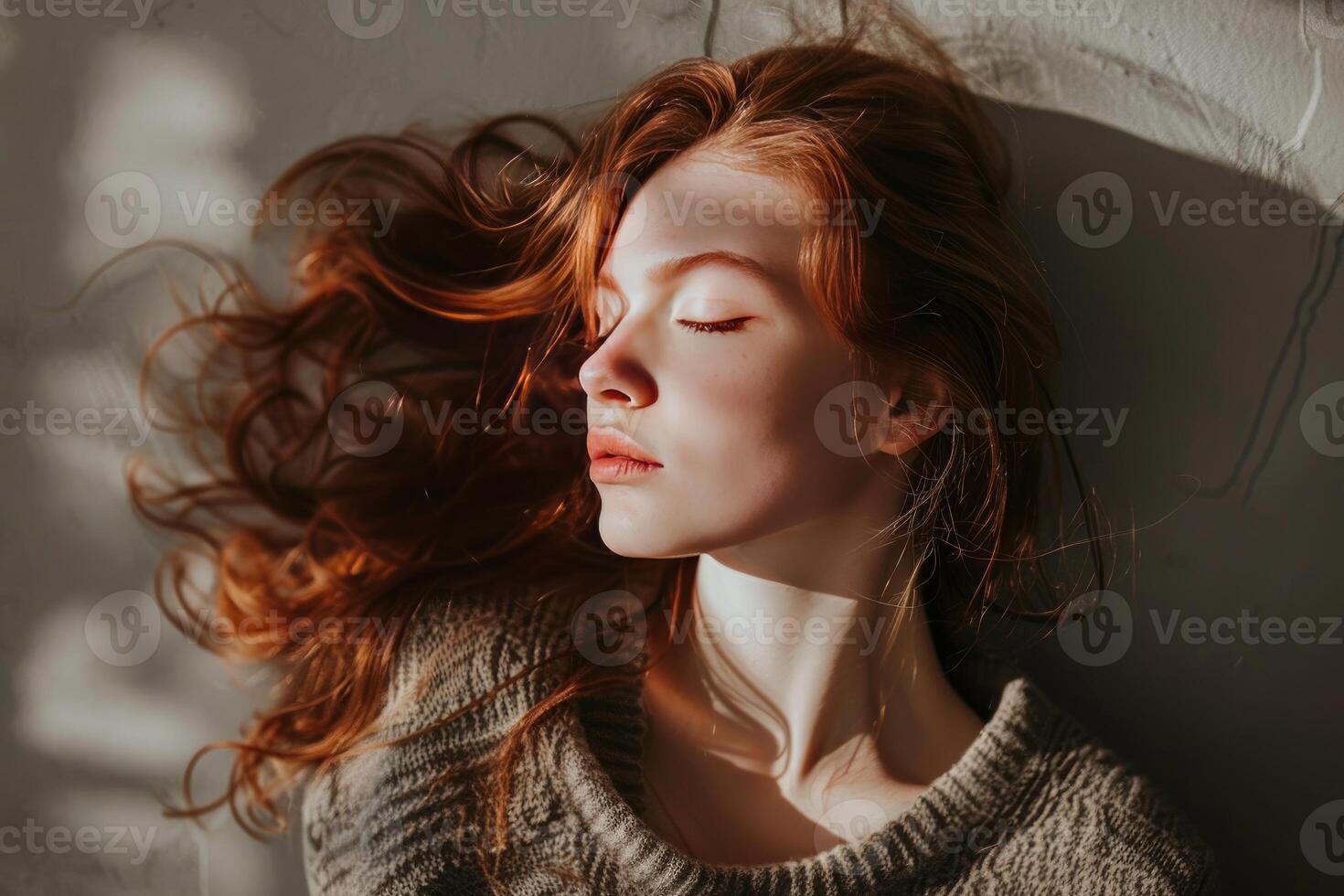 Redhead model resting on floor with eyes closed, enjoying sunlight photo