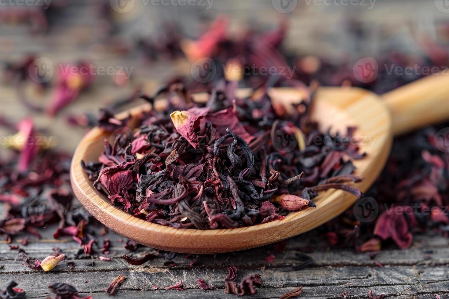Dried hibiscus petals resting in wooden spoon on rustic wooden surface photo