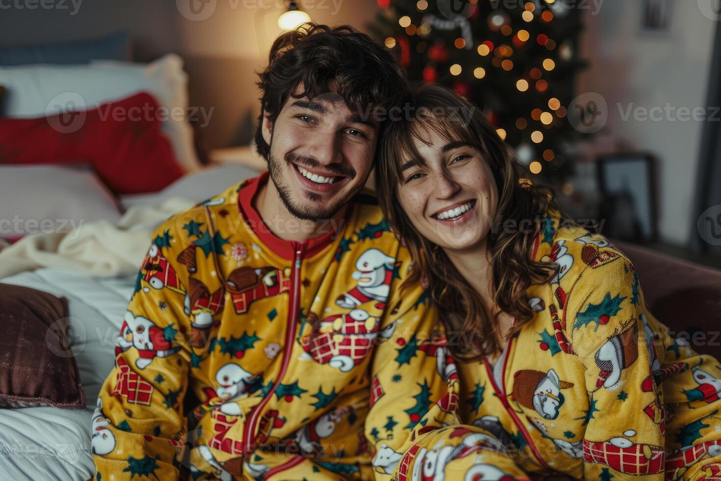 Happy couple wearing matching pajamas posing in front of christmas tree photo