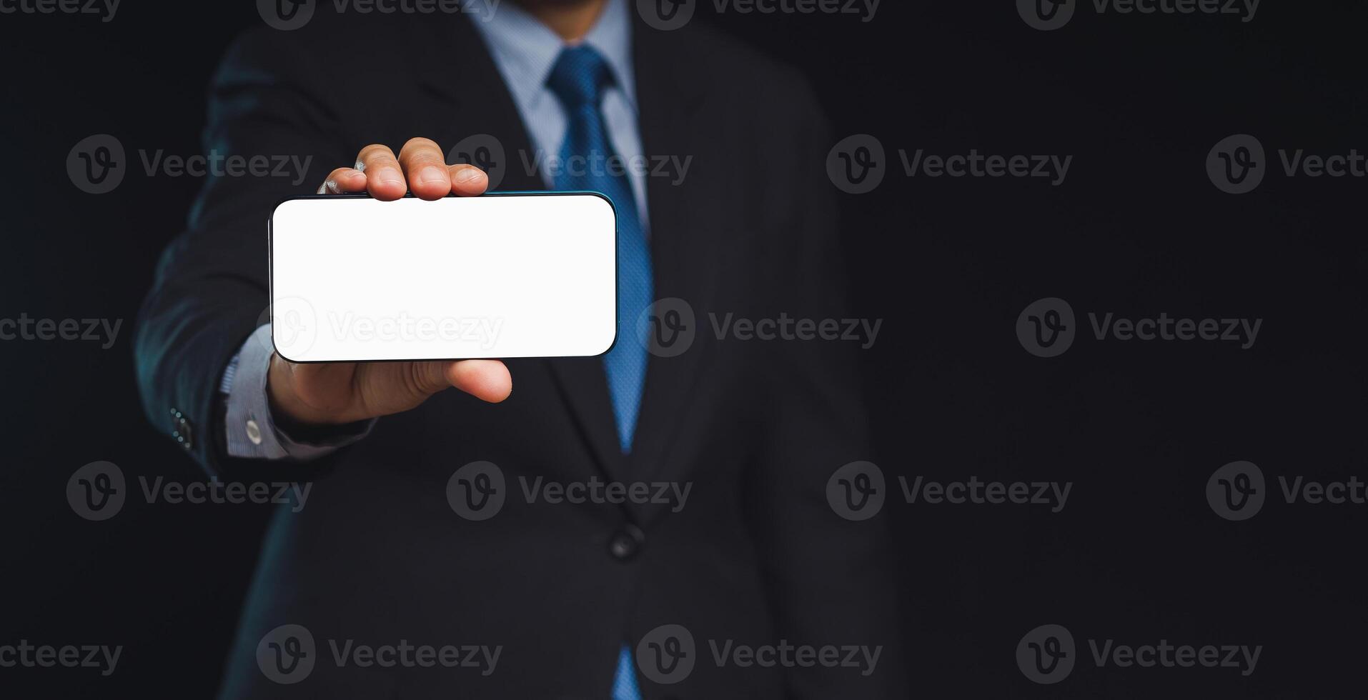 Close-up of a hand holding a white blank screen smartphone against a black background. photo