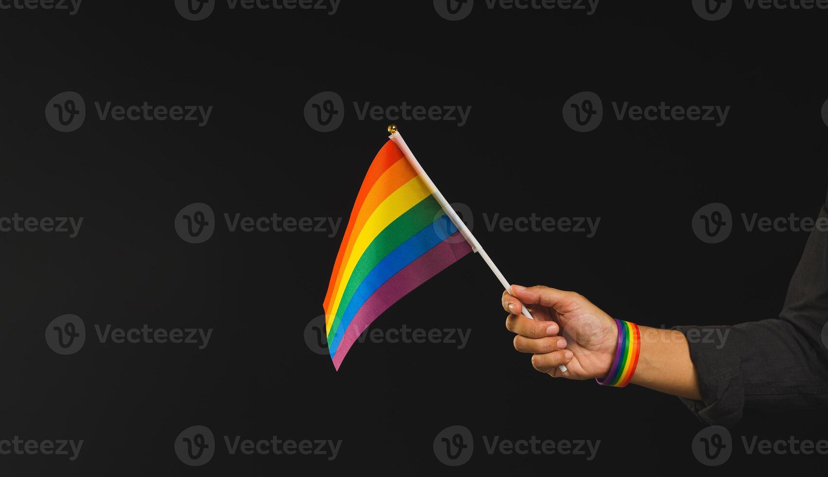 Close up of the rainbow flag showing in hand against a black background. photo