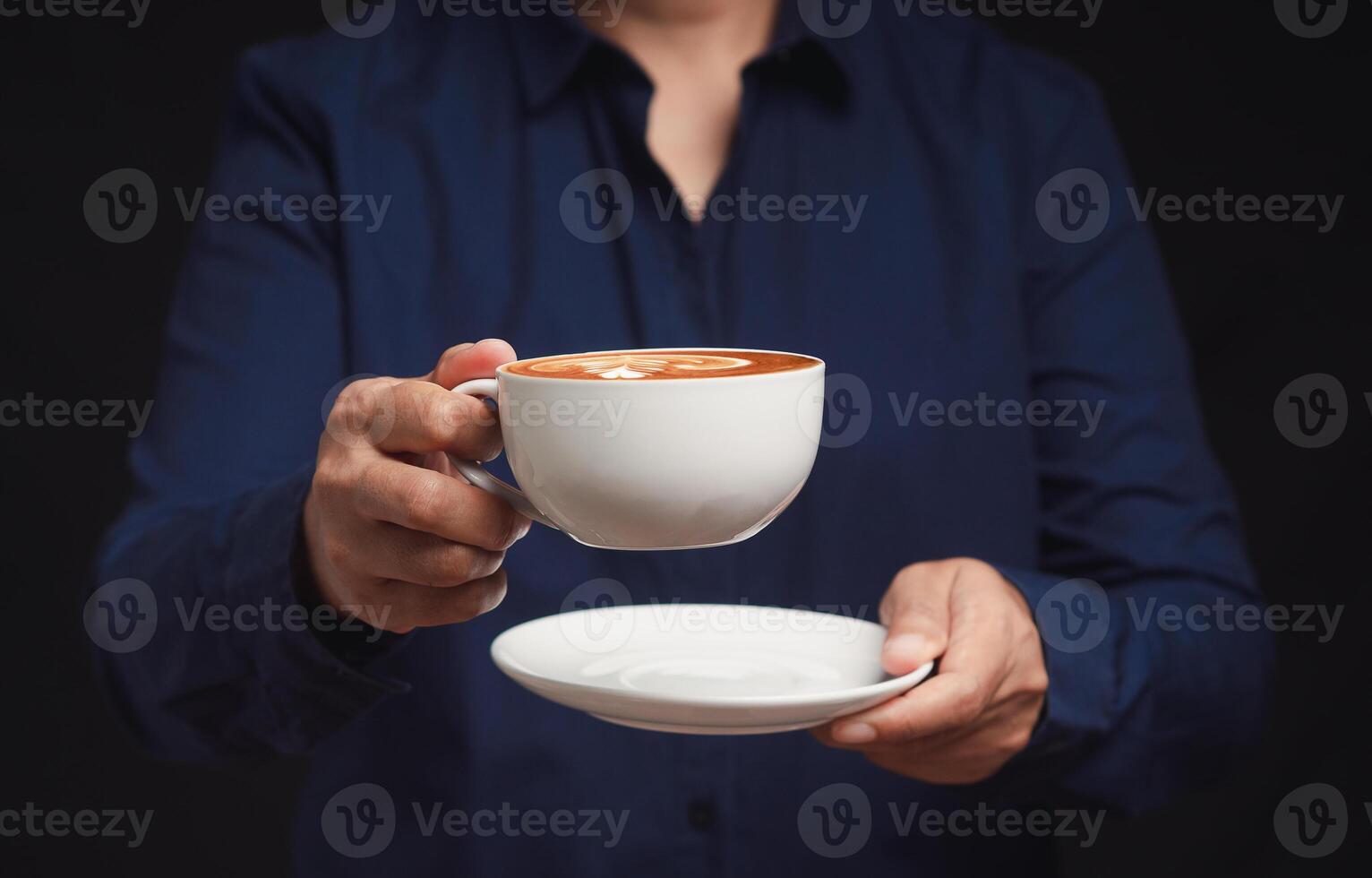 Close-up of hands holding a coffee cup against a black background photo