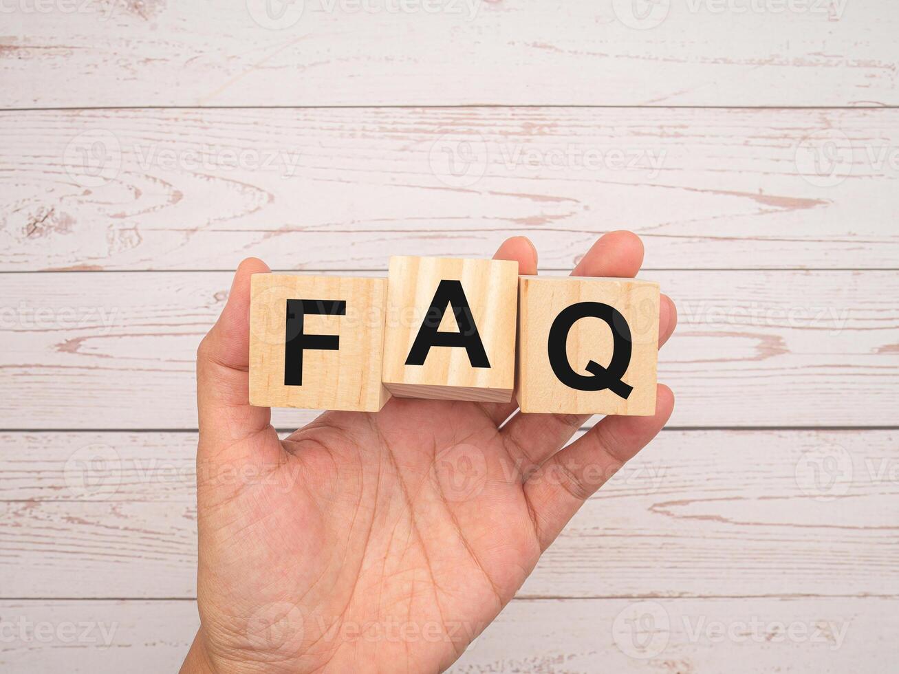 FAQ. Frequently asked questions. Wooden cubes with the letters F, A, and Q in hand over a wooden table photo