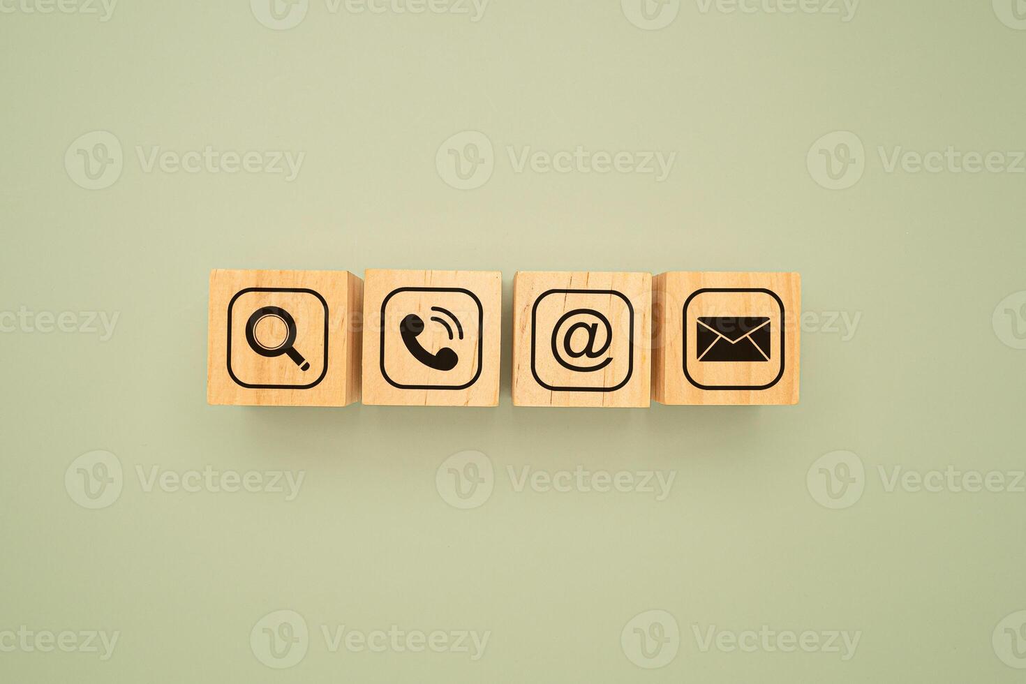 Top view of wooden cubes with symbols of a magnifying glass, mobile, address, and email on a green background. Flat Lay. photo