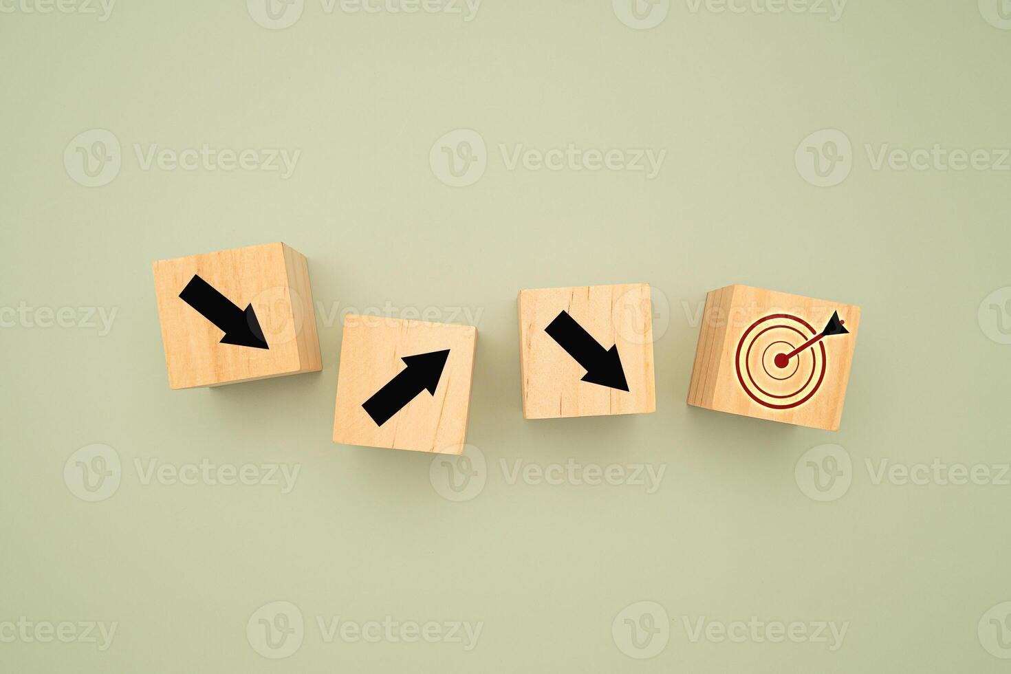 Wooden cubes with black arrows pointing to the dartboard icon on a green background photo