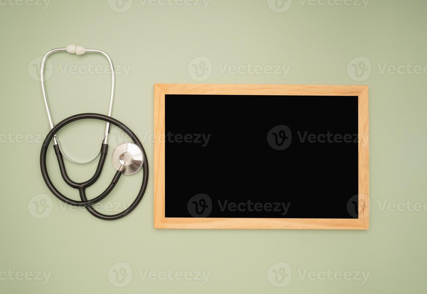 Top view of a stethoscope and a blank mini chalkboard on a green background photo