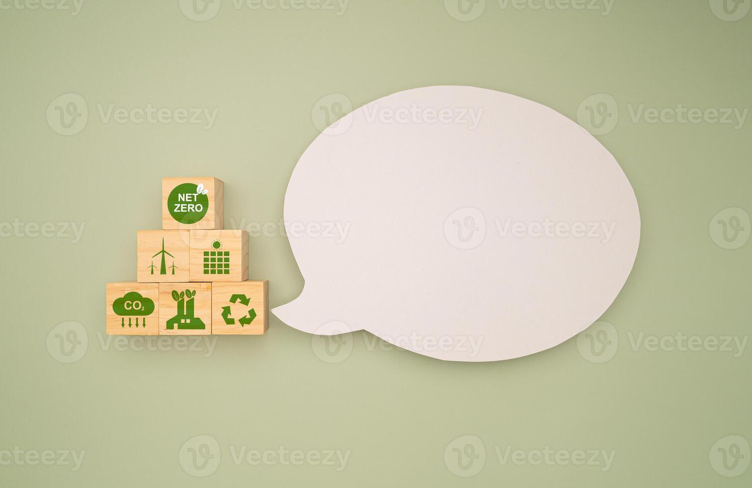 Wooden cubes with eco-friendly icons and a blank white speech bubble on a green background photo