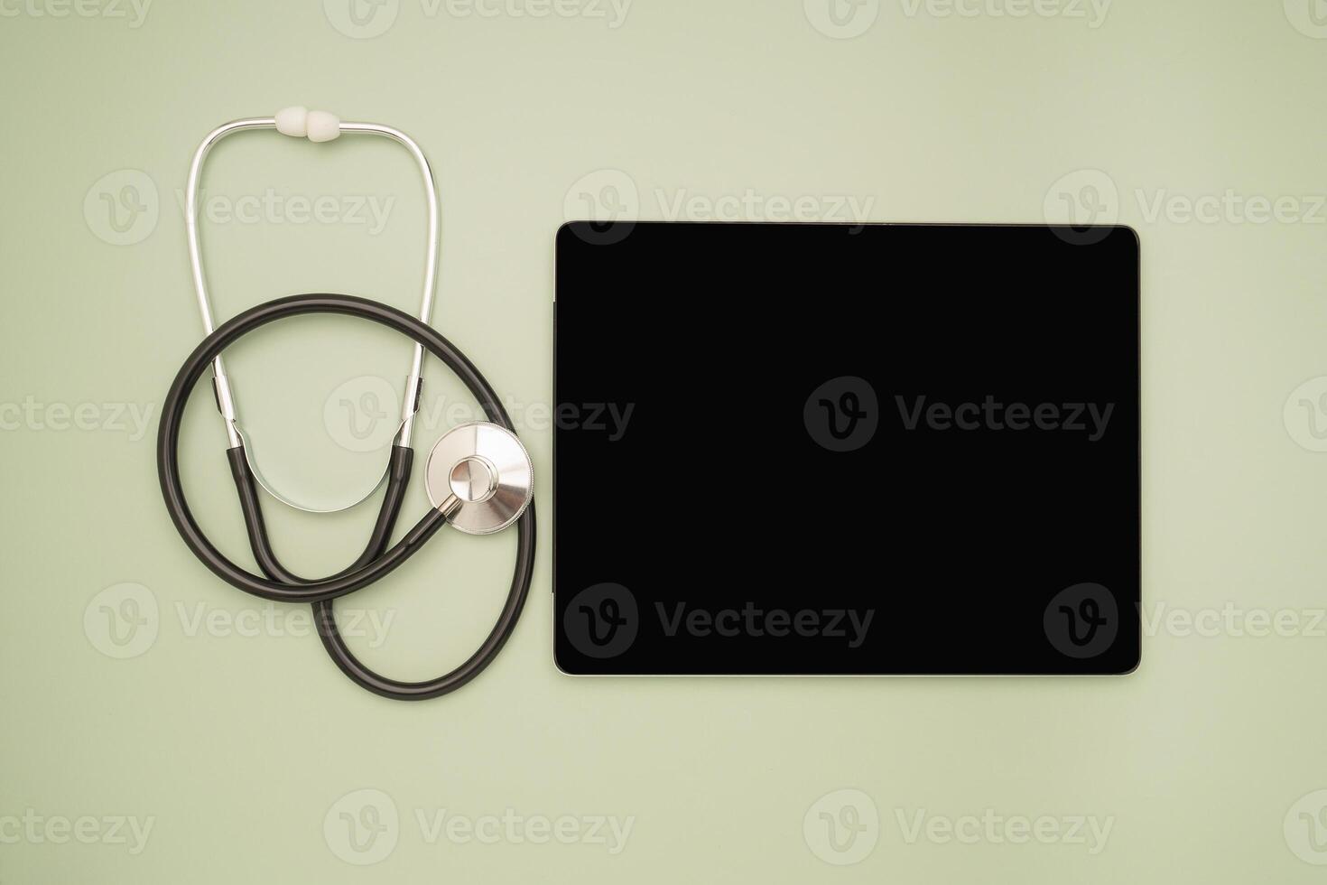Top view of a stethoscope and a blank screen tablet on a green background photo