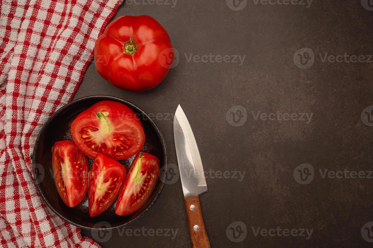 Close-up of fresh tomatoes in a black bowl and a knife on a table. Top View. photo