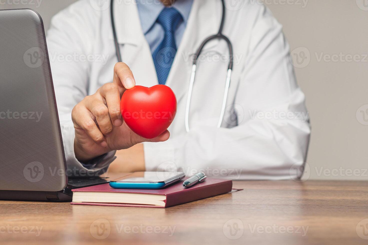 Close-up of a hand holding a red heart shape symbol while sitting in the hospital. photo