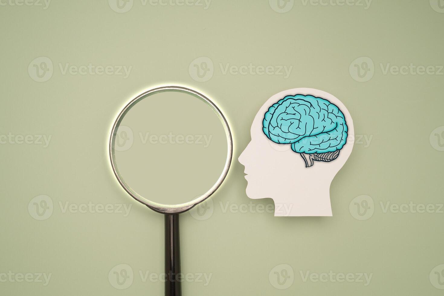 A brain shape symbol and a magnifying glass on a green background photo
