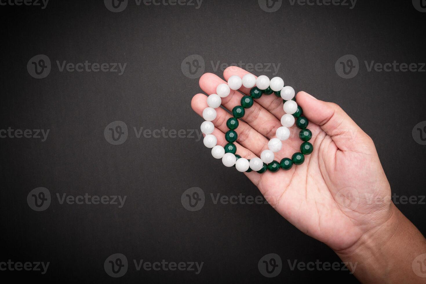 Jade bangles or bracelets in hand against a black background. Space for text. photo