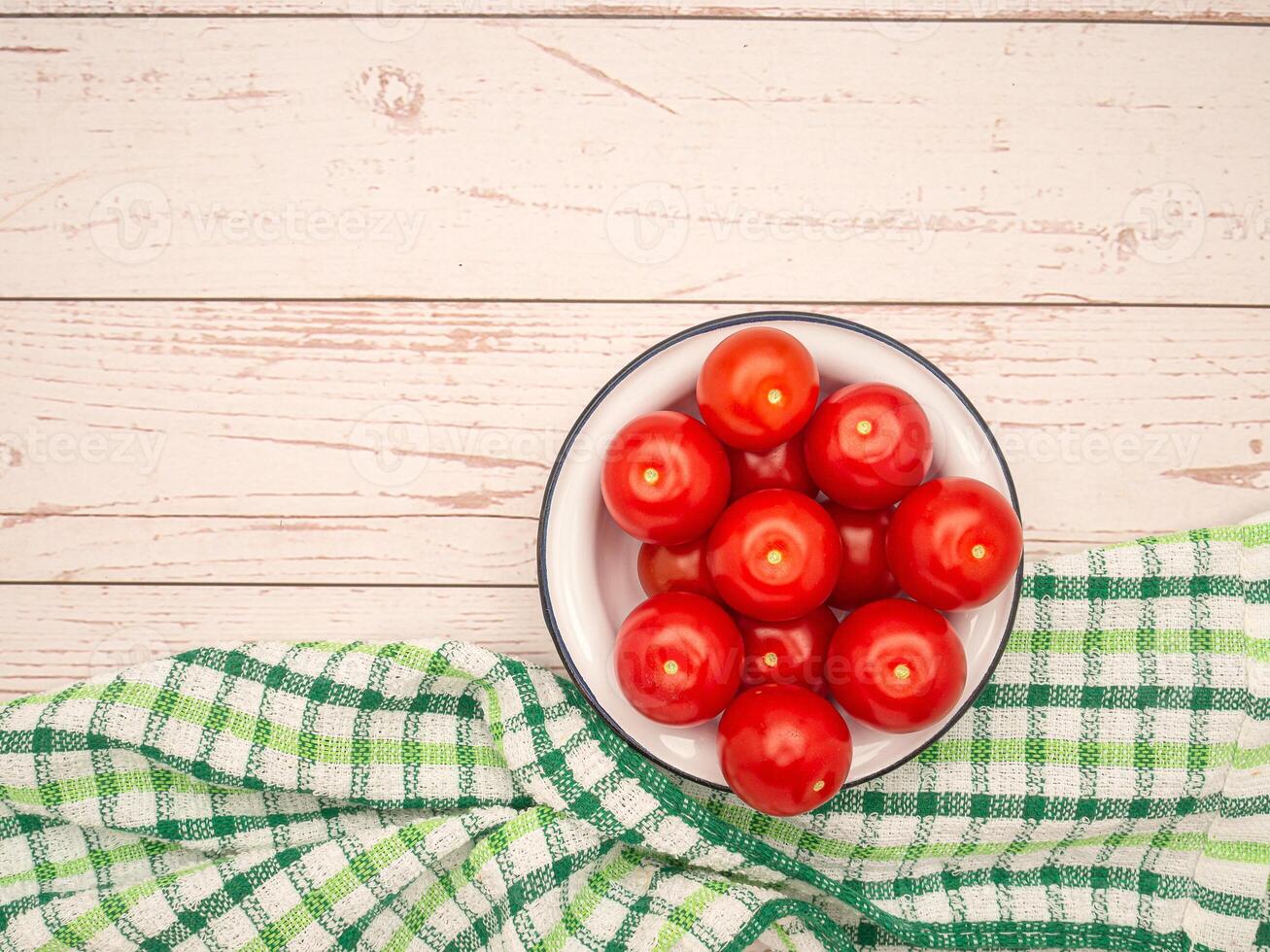 Top view of fresh tomatoes on a white plate with a cloth on a wooden table photo