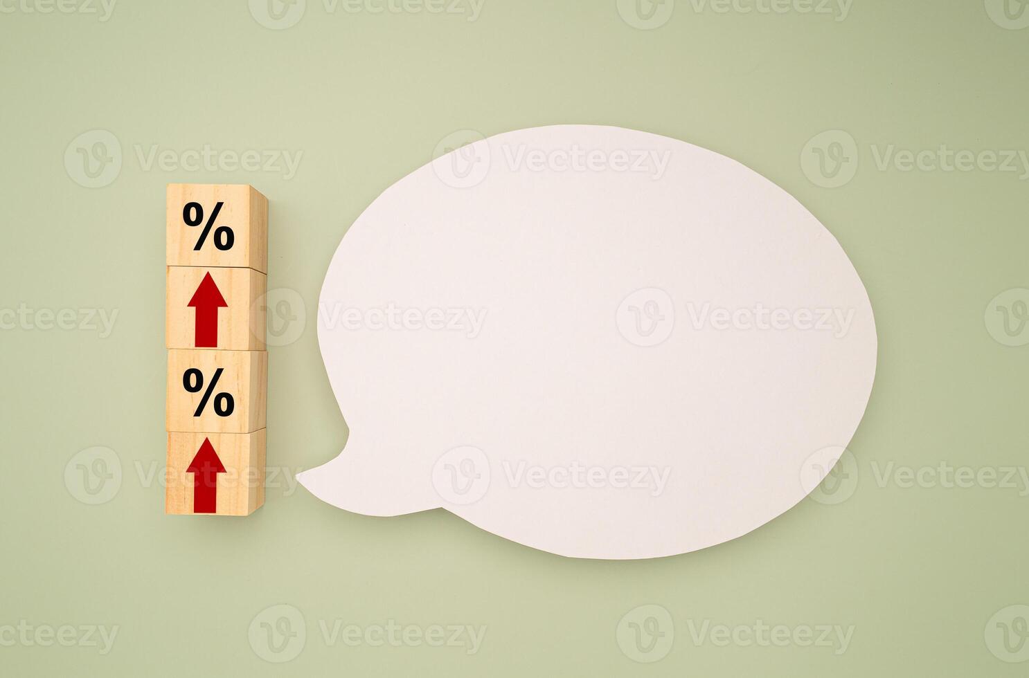 Wooden blocks with red arrows up and percentage symbols and a blank white speech bubble on a green background photo
