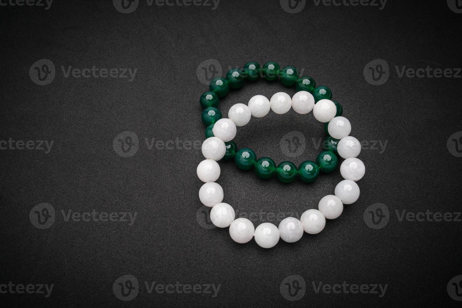 Top view of white and green jade rings on a black background. Space for text. photo