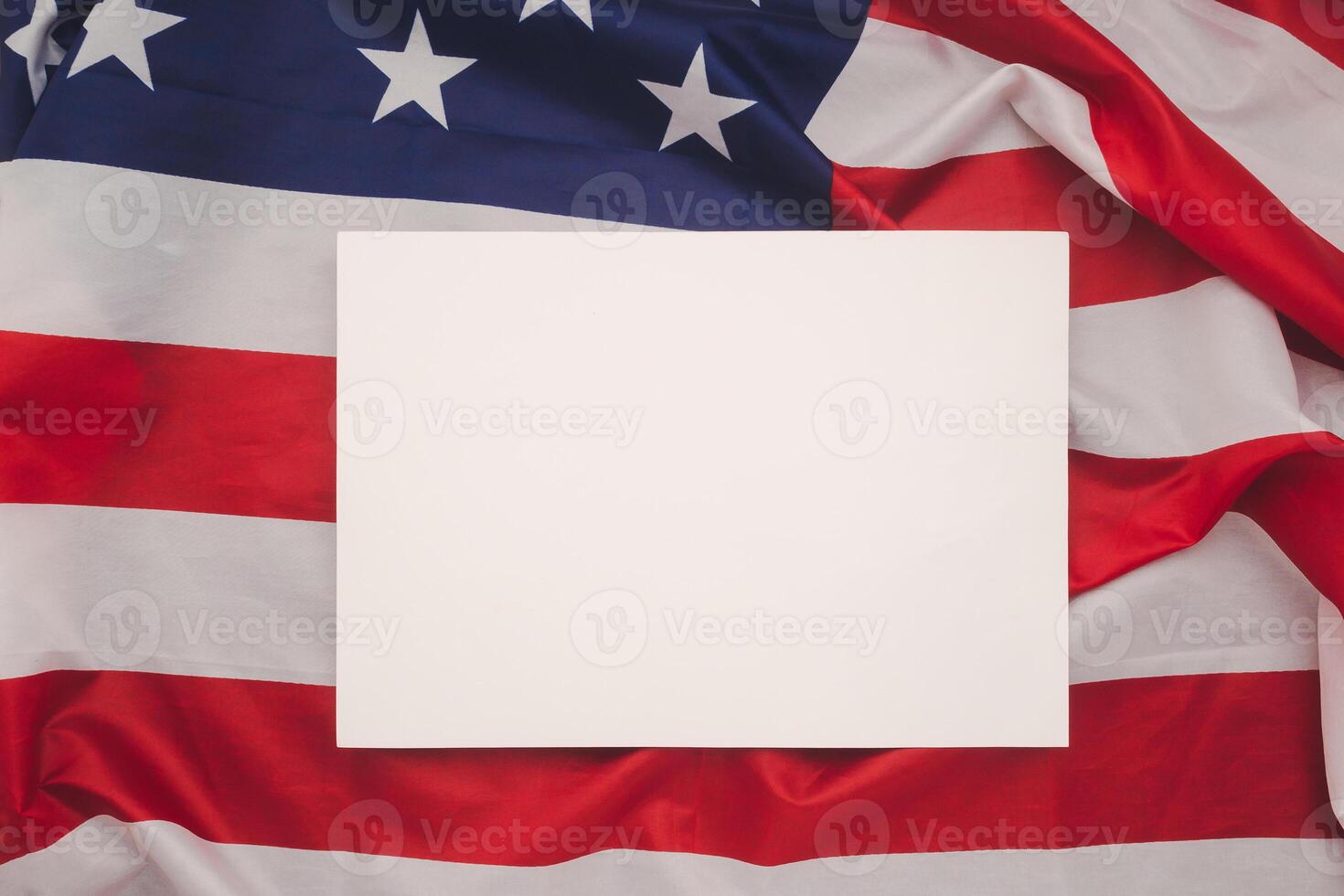 A blank white paper over the American flag. Top view. photo