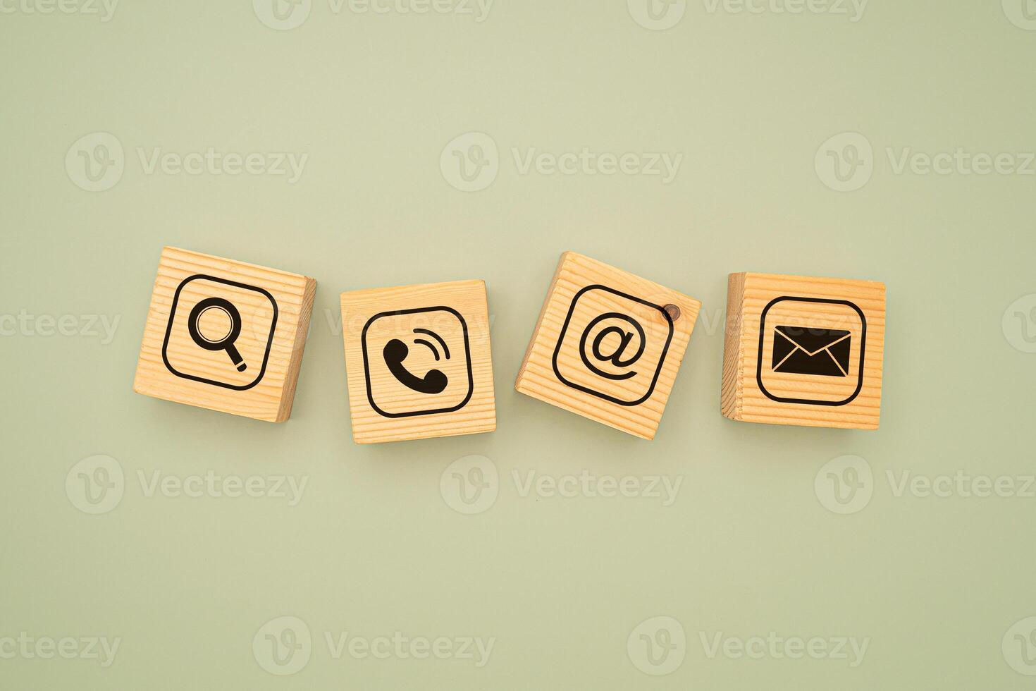 Top view of wooden cubes with symbols of a magnifying glass, mobile, address, and email on a green background photo