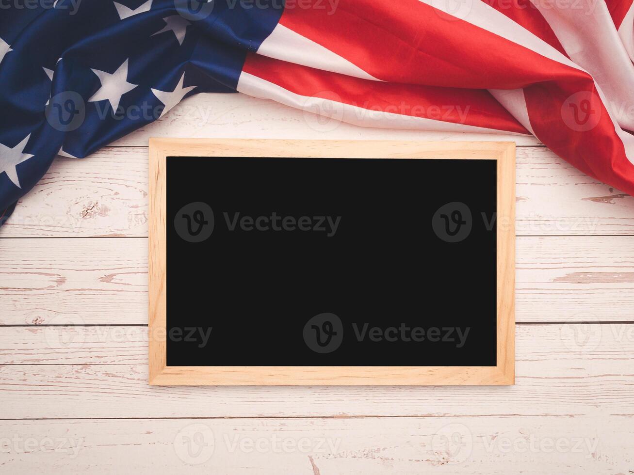 Part of the American flag and a mini chalkboard on a wooden table. Space for text. photo