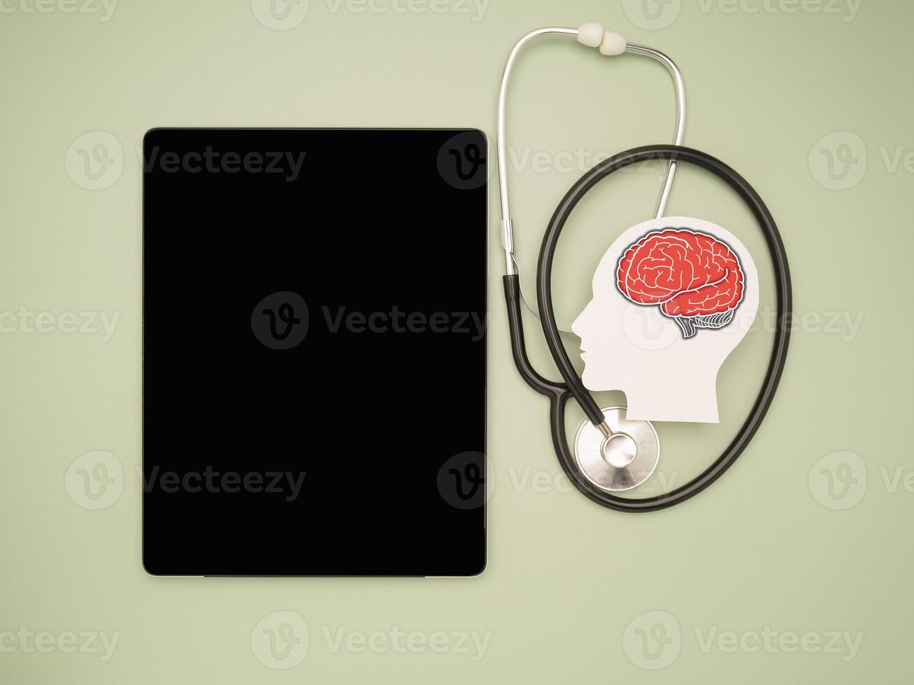 A brain shape symbol, a stethoscope, and a tablet on a green background photo